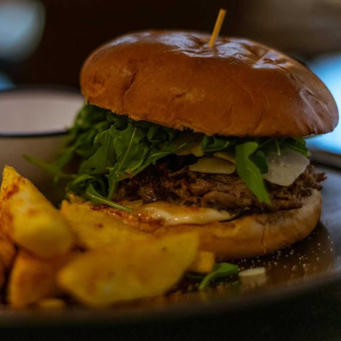 Hamburguesa de cordero deshilachado en pan brioche con rúcula, foie casero y grana padano