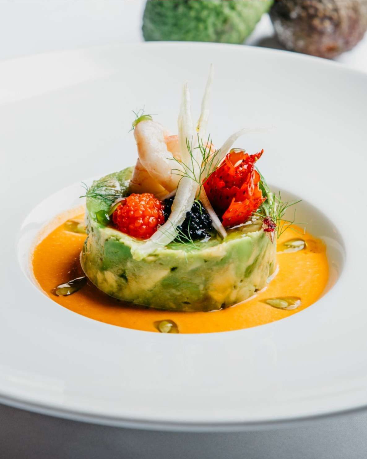 Timbal de gambas y aguacate sobre fondo de salmorejo